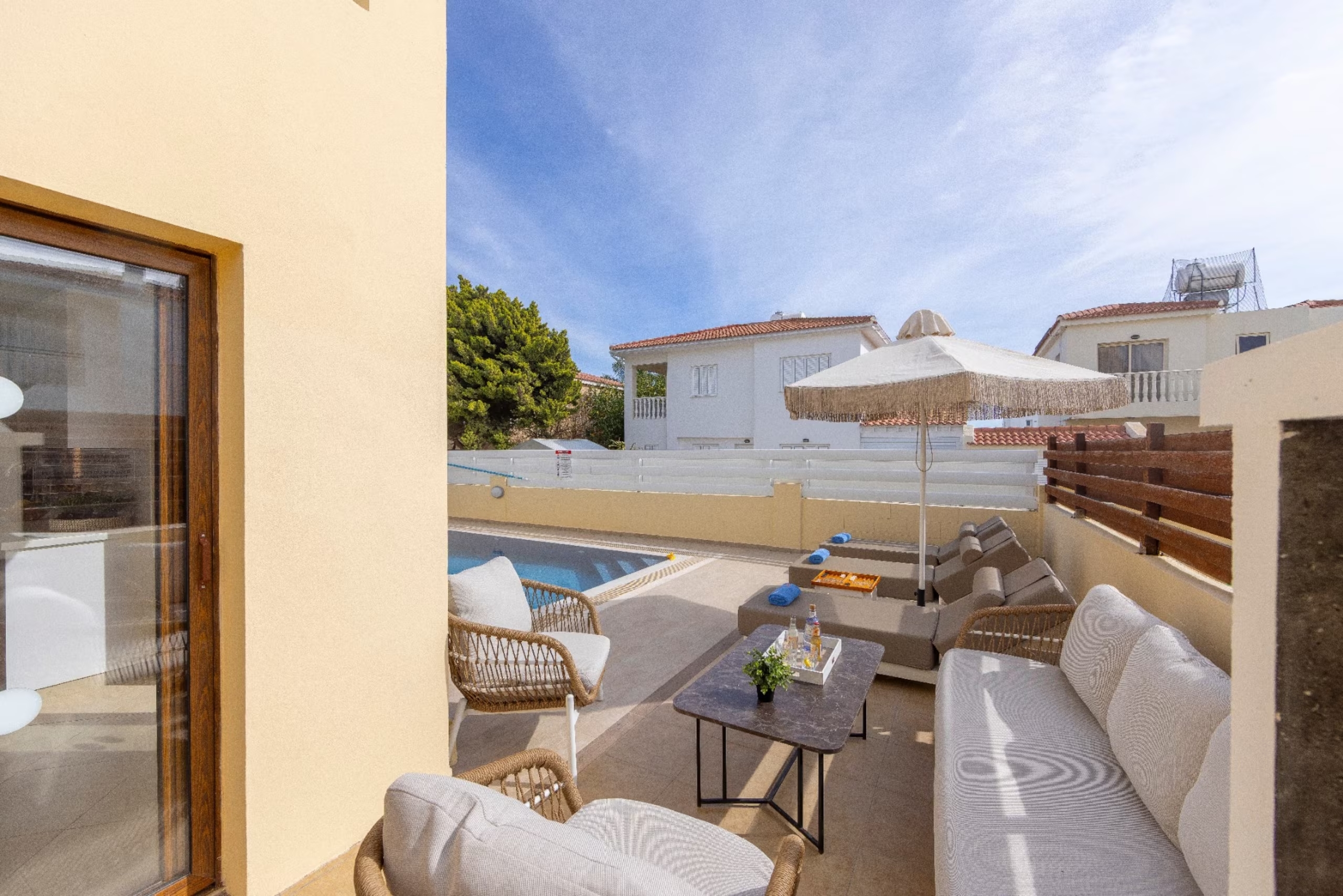 Villa Poseidon's outdoor lounge with sofa, wicker chairs, sunbeds and swimming pool