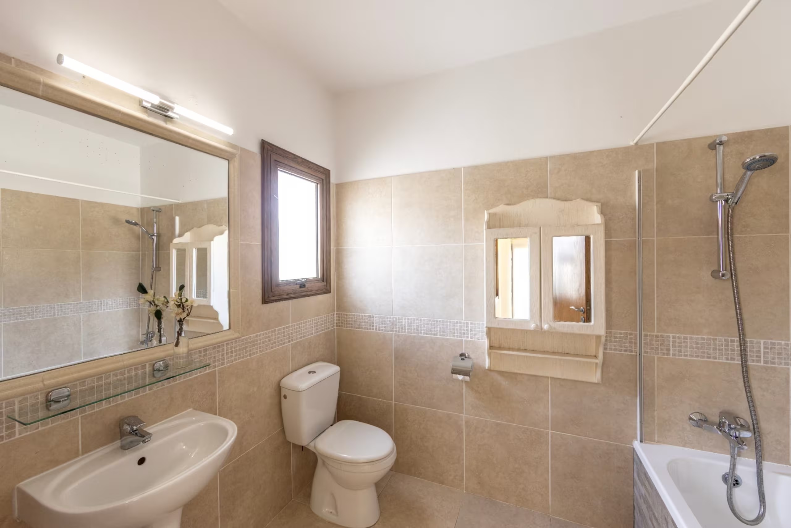 Villa Poseidon's main bathroom with bathtub, overhead shower, washbasin and toilet