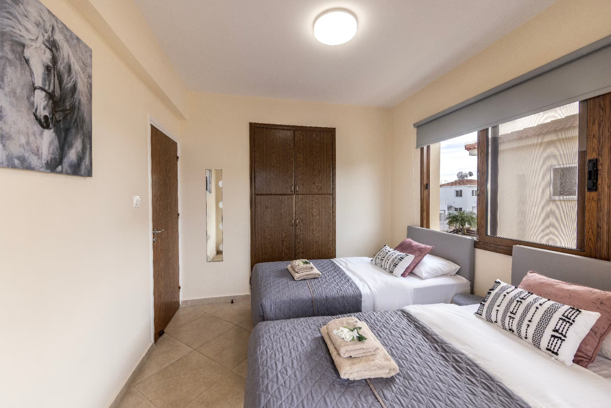Twin bedroom with two single beds, grey bedding and wooden wardrobe
