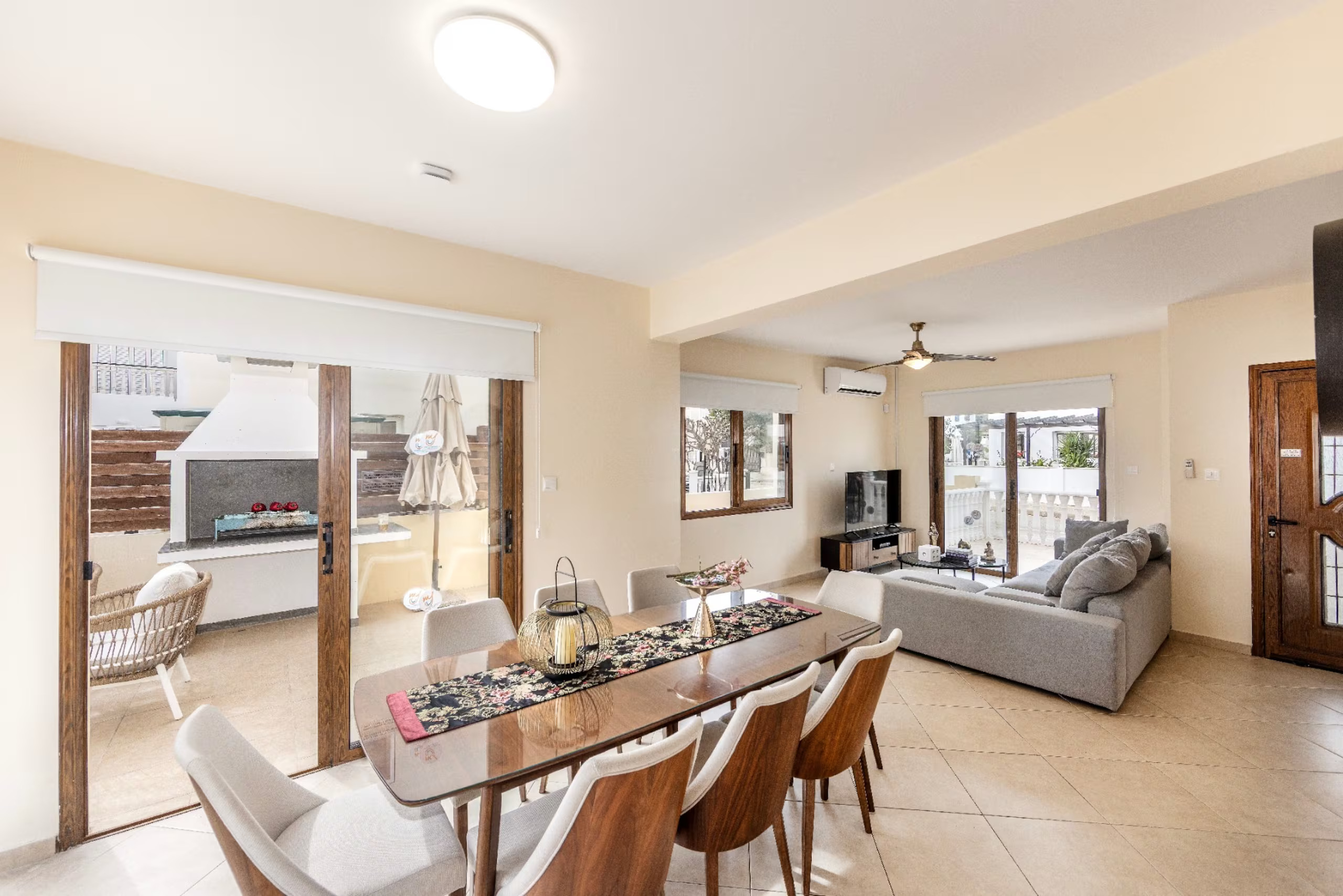 Indoor dining table and lounge with sliding doors opening towards the built-in outdoor barbecue