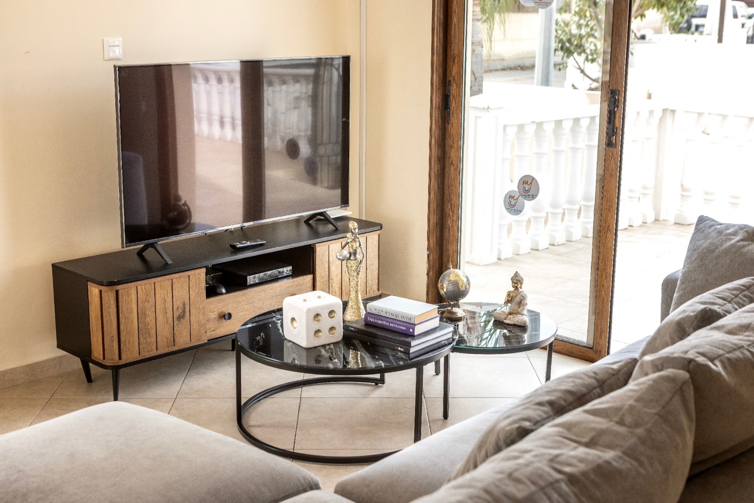 Flat-screen television and coffee tables beside the grey sofa in Villa Poseidon